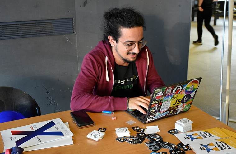 Hacker typing on a GNU/Linux laptop full of stickers