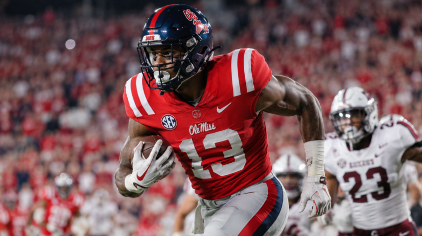 Dae’Quan Wright carries the football in an Ole Miss Rebels uniform during a college football game under stadium lights.