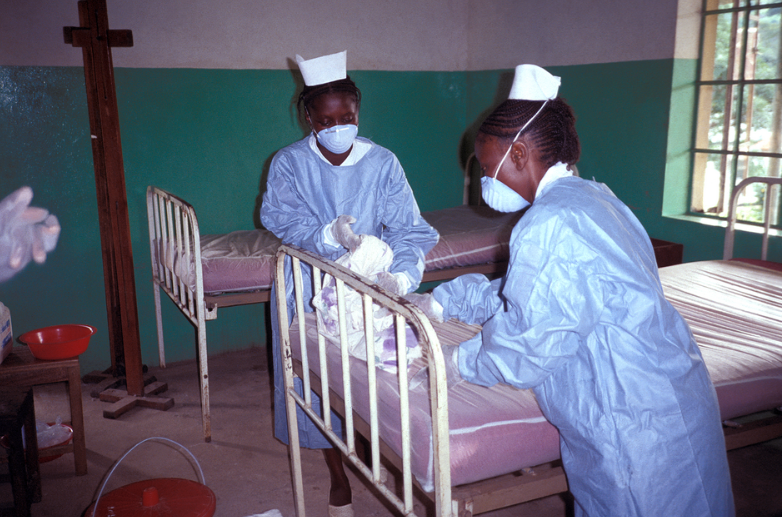 Captured in 1995, this image depicts two Zairian nurses, who were in the process of changing the bedding within the Ebola isolation ward inside Kikwit General Hospital, located in what was known as the country of Zaire, which has since become the Democratic Republic of the Congo