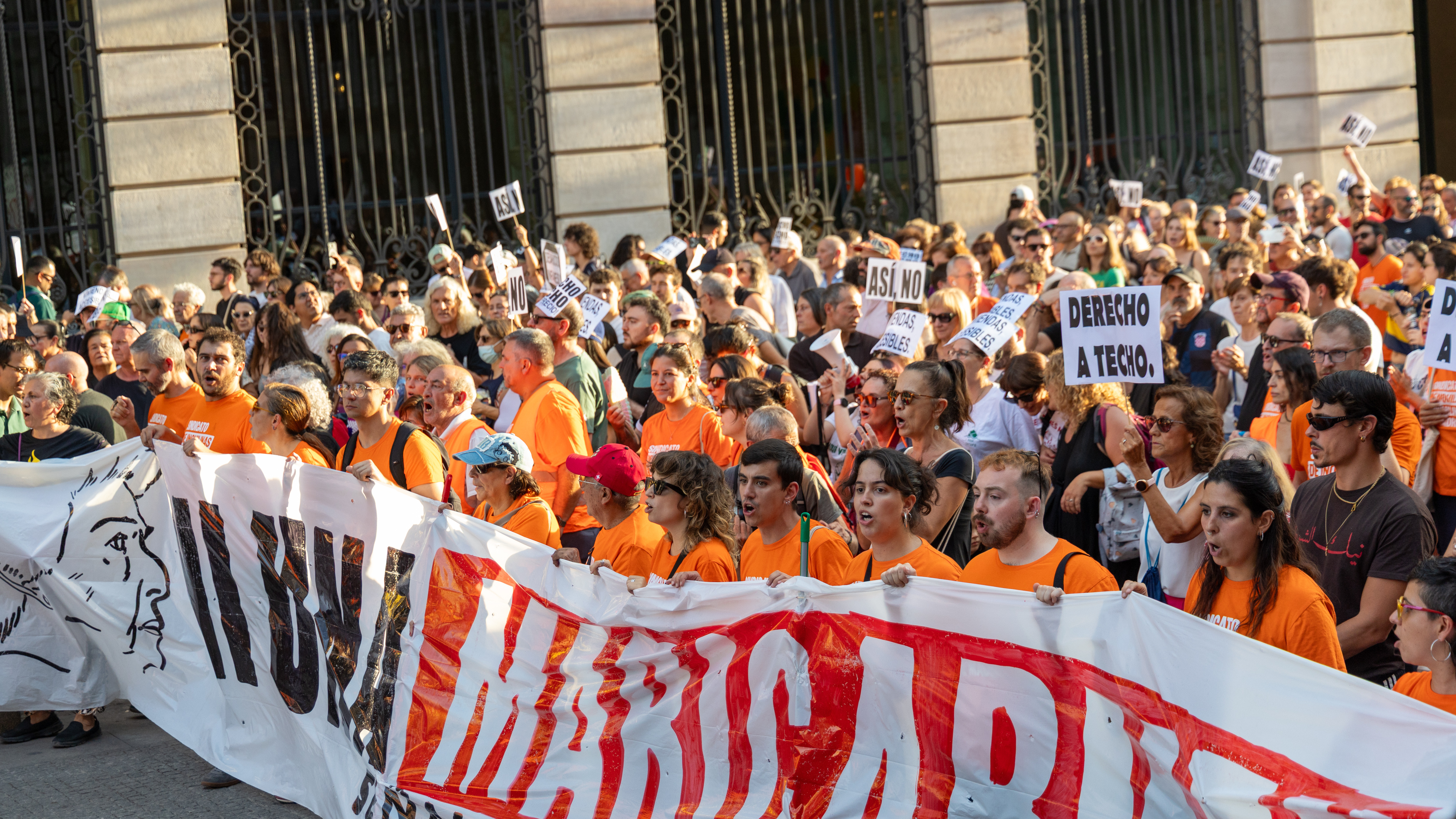 Demonstrators at the head of a march for the right to housing carry the main banner, bearing the motto "Ni una Maricarmen más" ("Not one more Maricarmen"), as they pass the Centro Canalejas complex
