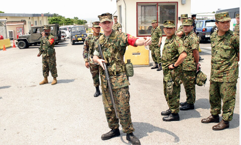 A US Marine Corps (USMC) Marine, Security Detail, Camp Foster, Marine Corps Base (MCB) Camp Smedley D. Butler, Okinawa, Japan, signals to his NCOIC that the driver of a suspicious vehicle
